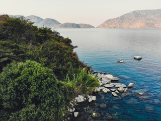 Aerial view of the vivid turquoise waters meet the rugged, rocky shoreline fringed with lush green vegetation, Cape Maclear, Southern Region, Malawi.