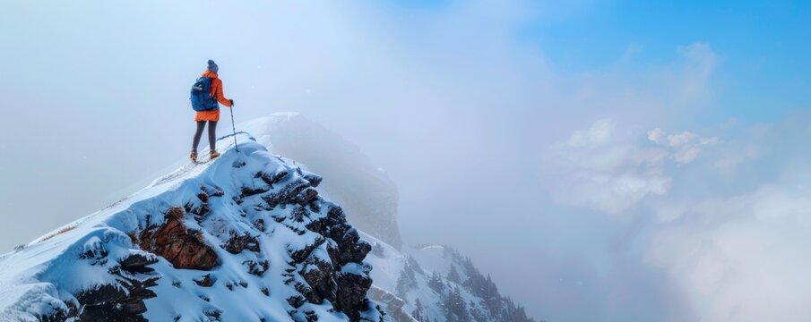 lone hiker with backpack and poles standing on snowy mountain peak above the clouds