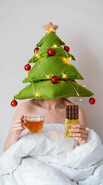 Relaxed New Year Christmas holidays in bed with pillow tree, festive ornaments, string lights, tea, chocolate treats, preholiday fatigue, holiday hustle, whimsical seasonal humor, playful