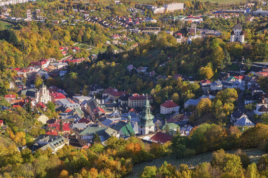 Aerial view of the Old Castle and Holy Trinity Column nestled among autumn foliage, with the town's red rooftops and church spires visible, Banska Stiavnica, Banska Bystrica Region, Slovakia.