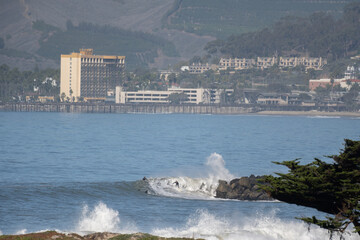 Surfer and his friends enjoying the waves off the jetty with hotel and pier in background