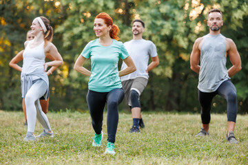 Group exercise session in a park during a sunny day with enthusiastic participants enjoying lunges