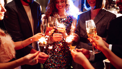 Glowing sparkles in hands. Group of happy people enjoying party with fireworks. Winter holiday.
