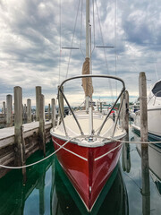 Beautiful Red Sailboat Docked in the Harbor on Lake Michigan. The boat is tied to the dock with a rope. Located in the Northern Michigan town of Harbor Springs, USA in Little Traverse Bay.