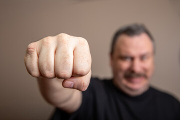 A man with a black shirt and a mustache is punching the air