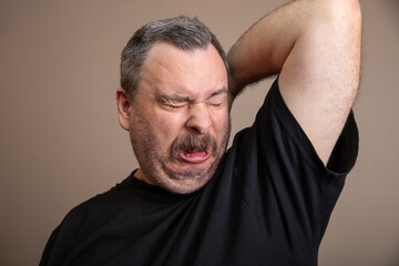 A man with a beard and mustache is wiping his face with his hand