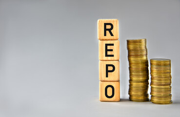 REPO - word on wooden cubes on the background of stacks of coins
