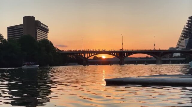 Austin Texas Congress Avenue Bridge at sunset with silhouette crowd waiting for bats and boats on Lady Bird Lake