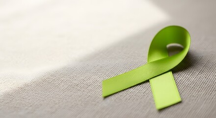Bright green awareness ribbon lying on a soft texture with sunlight for mental health awareness concept and advocacy