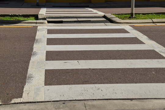 A crosswalk with a white stripe and a brown stripe