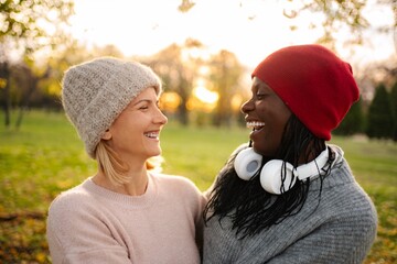 Diverse women friends laughing together outdoors during autumn