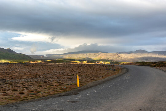 Icelandic landscape with asphalt road and mountains in cloudy weather.