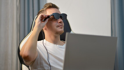 Man Putting On Wearable AR XR Smart Glasses While Using Laptop