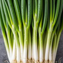 Obraz premium Close-up shot of fresh green onions with white stems and roots, ready for cooking.