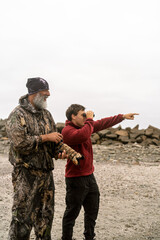 Naklejka premium Men birdwatching, observing wildlife with binoculars, telephoto lens