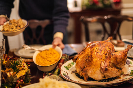 Christmas dinner scene with a festive roasted turkey and traditional holiday side dishes being served at a warm, decorated family table.