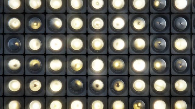 Flashing bright retro studio spot lights or bulbs grid in dark environment making random pattern, repeating animation. 