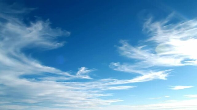 Serene landscape of a clear blue sky with wispy white clouds over a flat white surface.