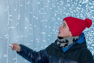 Teenage Boy in Winter Clothing Admiring a Christmas String Light