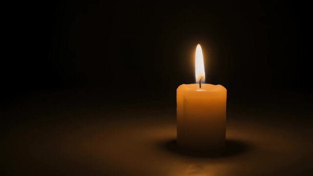 A solitary lit candle casting a warm and gentle glowing light in a dark background