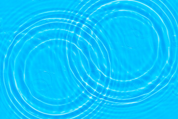 Blue water with ripples on the surface. Defocus blurred transparent blue colored clear calm water surface texture with splashes and bubbles. Water waves with shining pattern texture background.