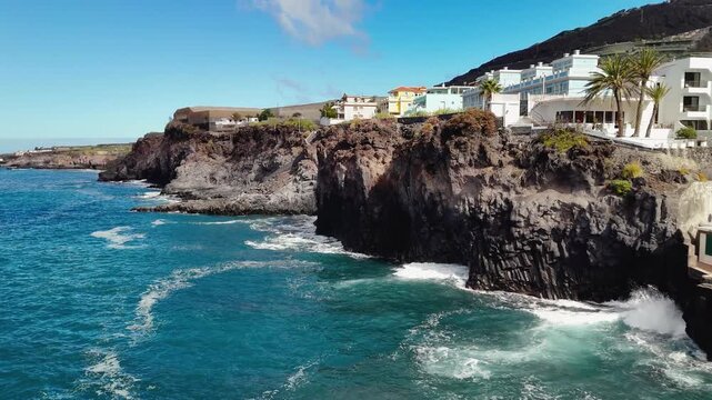 Aerial drone shot of colorful apartments and houses built into the cliffside overlooking the Atlantic Ocean in Puerto Naos, La Palma, Canary Islands, Spain.