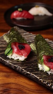 Raw red tuna sushi rolls wrapped in dried seaweed with caviar on a rectangular plate. Motion-control shot moving across the food. 