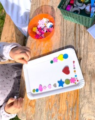 Children's hands create a photo frame, decorating it with glitter and stickers.
