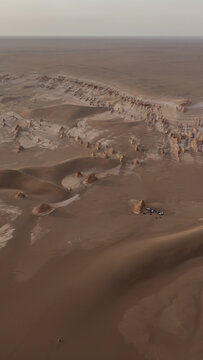Aerial view of wind-carved yardangs and dunes create a surreal, textured landscape under a muted sky, Shahdad, Kerman Province, Iran.