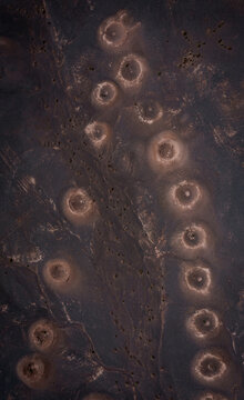 Aerial view of mysterious circular formations puncturing the arid landscape, their pale rims contrasting with the dark earth, Shahdad, Kerman Province, Iran.