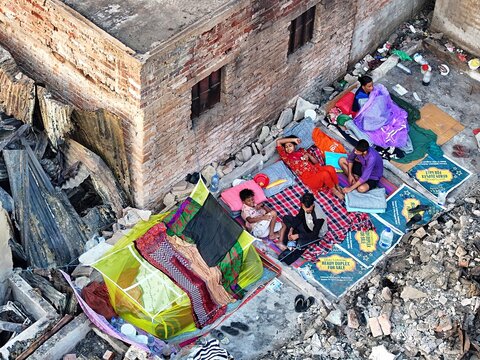 Dhaka, Bangladesh - 28 November 2025: Aerial view of Korail slum residents, their vibrant blankets and colorful clothes a stark contrast to the rubble and devastation around them.