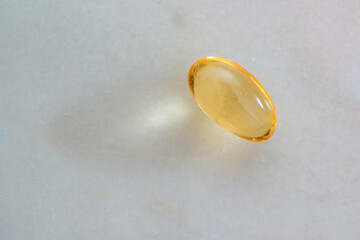 Omega 3 translucent capsule tablet on a solid surface.