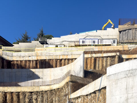 View of a construction site with exposed earth and concrete walls under a clear blue sky, a crane towers, Sarıyer, Istanbul, Turkey.