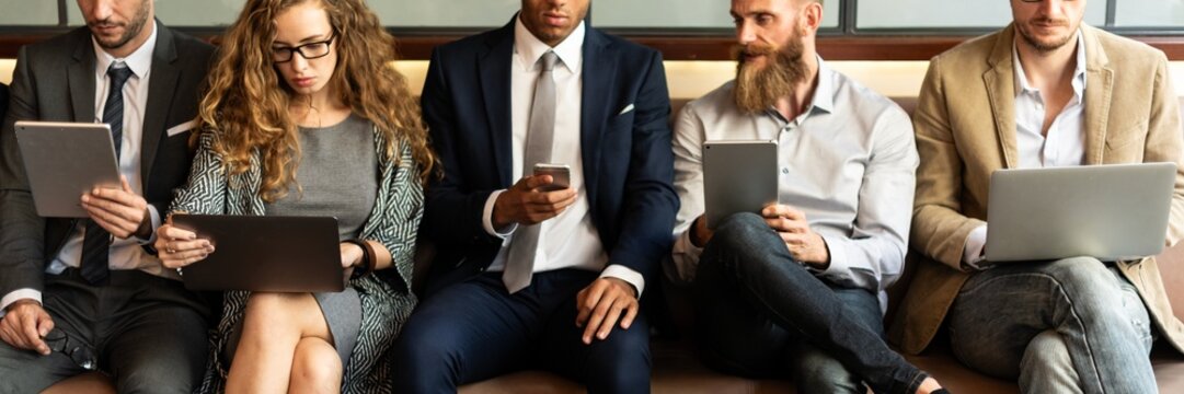 Diverse group of professionals sitting, using laptops and tablets. Business attire, technology. Men and women engaged in digital work, tech-savvy setting. People using digital devices, social media. - Powered by Adobe