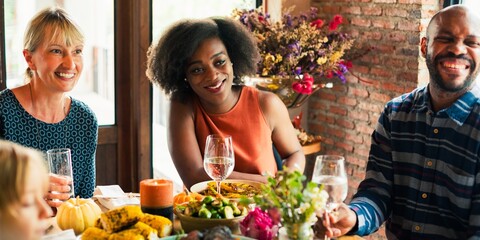 A joyful gathering featuring a diverse group of friends, including a Black woman, a Caucasian woman, and a Black man, enjoying a delicious meal together, sharing laughter and good times.