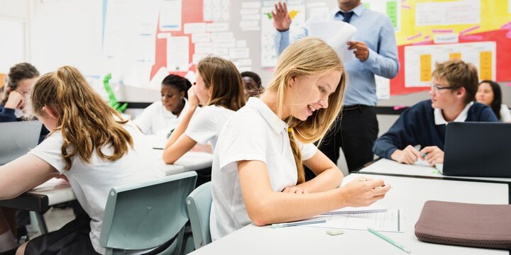 Students in a classroom setting, focused on learning. Diverse group of students engaged in study, with a teacher guiding the classroom activities. Teacher teaching a diverse high school class. - Powered by Adobe