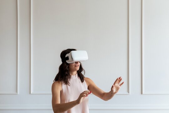 Woman use VR headset exploring virtual reality. Woman immersed in VR, interacting with virtual reality environment. VR technology experience. Woman experience VR technology in modern room