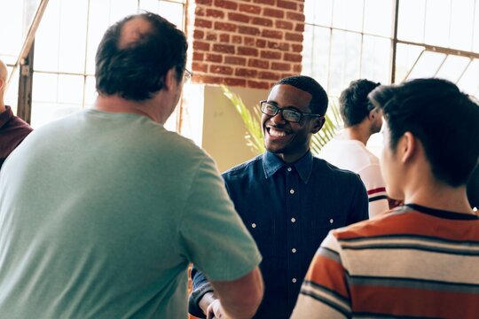 Diverse group in casual attire socializing in a modern loft for new community and connection. Diverse group communicating and networking in a bright for new community and connection. - Powered by Adobe