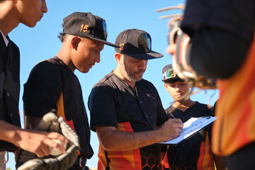 Coach explaining tactics to young baseball team members during a game break