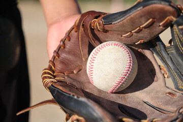 Baseball glove catching a white ball on a sunny day signifying sports and play