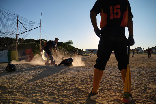 Players on a dusty field during a baseball game, one sliding under the tag
