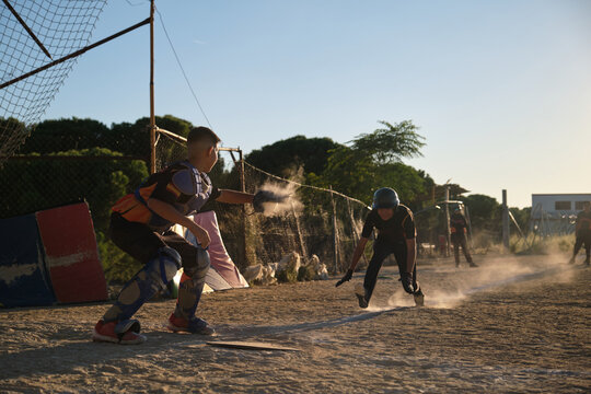Youth baseball players sliding into home plate, creating a cloud of dust - Powered by Adobe