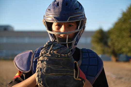 Young baseball player wearing catcher's gear, holding a glove