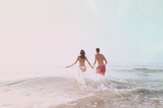 Happy couple running into the water