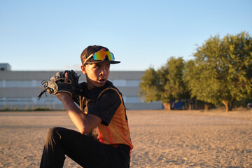 Young baseball pitcher in uniform with glove ready to throw during a game