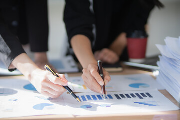 Smiling Asian businesswoman shaking hands with colleagues in office meeting, working together to plan corporate strategy, documents, contracts and work as a successful team.