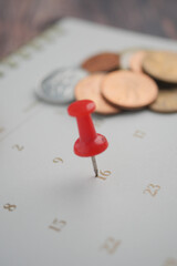 Calendar day marked with a pin and coins scattered around