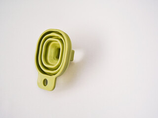 A flexible green rubber folding funnel isolated on a white background. A practical contemporary household item.