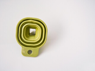 A flexible green rubber folding funnel isolated on a white background. A practical contemporary household item.