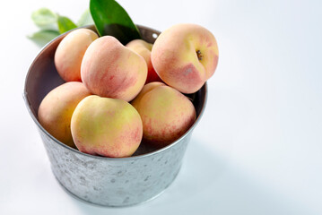 A metal bowl with fresh peaches 